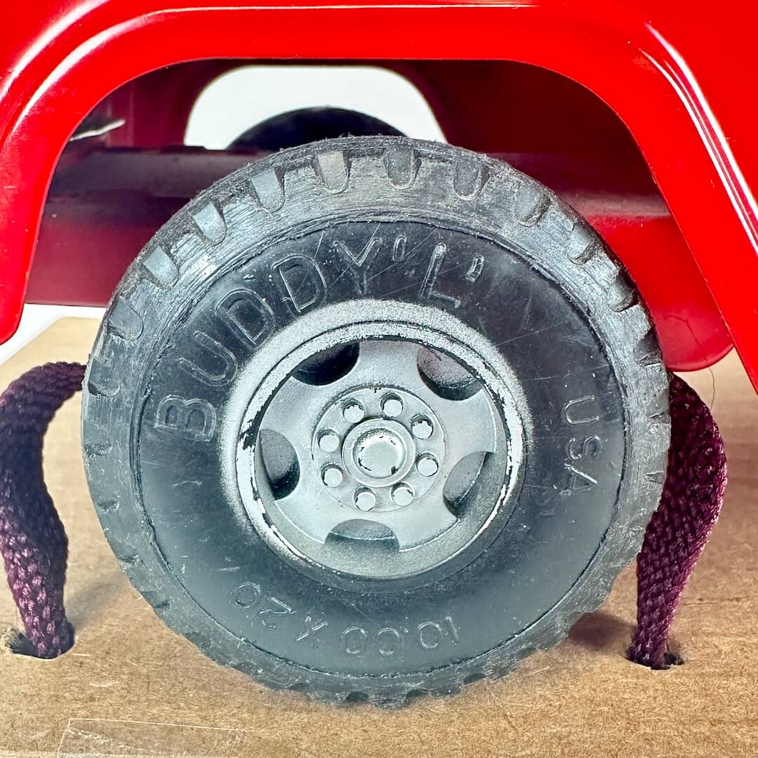 Toy truck tire with 'Buddy L' branding on a red toy truck.