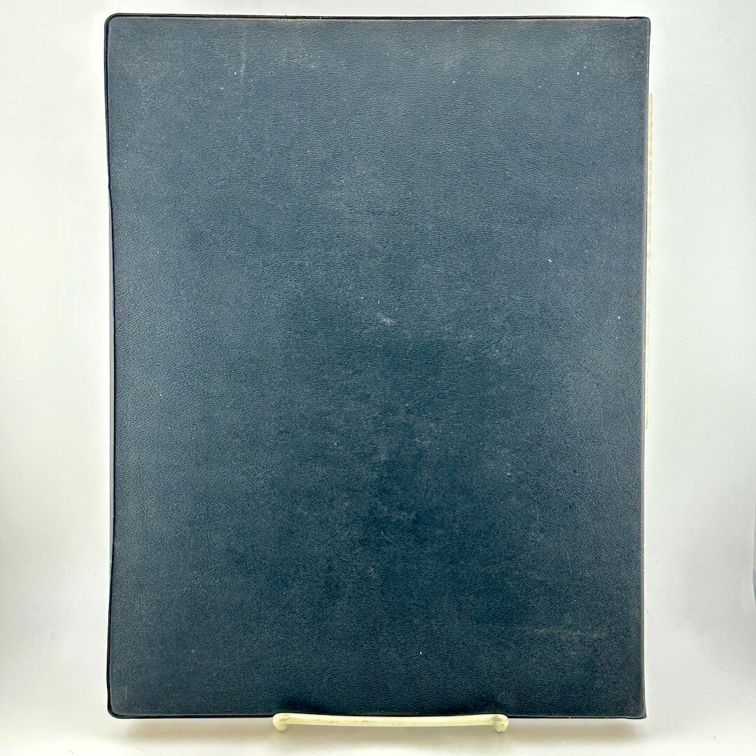 Black faux leather bound book against white background.
