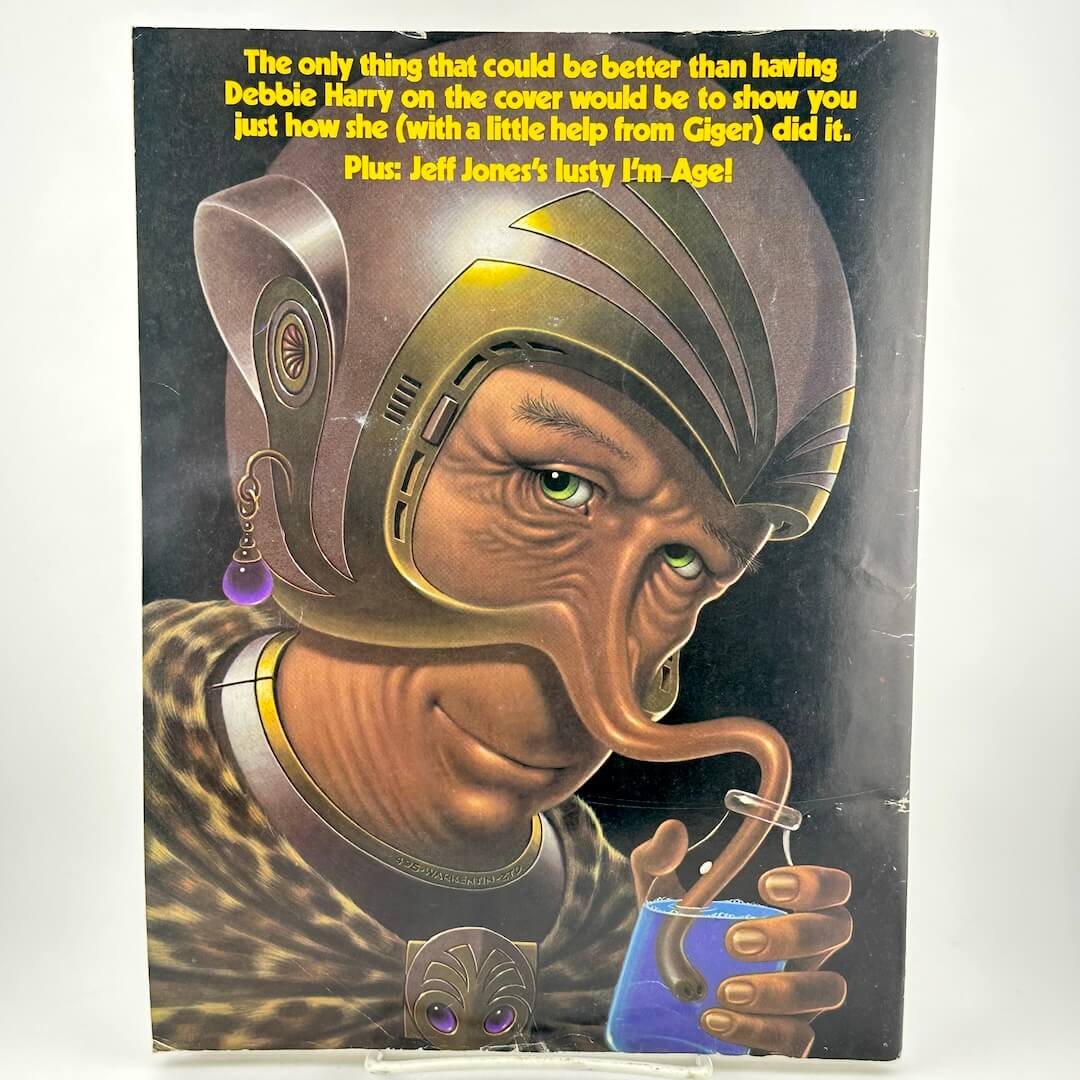 Back cover of magazine with illustration of man drinking blue liquid from snout, wearing a helmet.