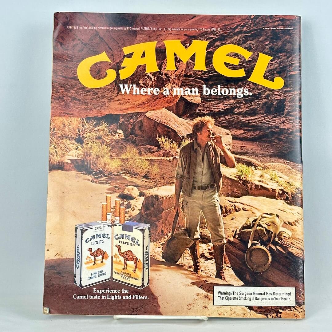 Back cover of magazine with full page ad for Camel cigarettes featuring a man smoking surrounded by rocky landscape.