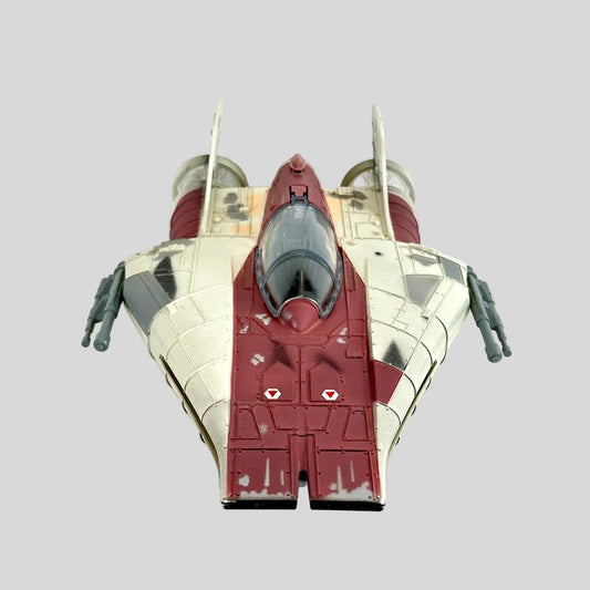 A toy futuristic starfighter spacecraft, featuring a cream and dark red color scheme with gray engine components.