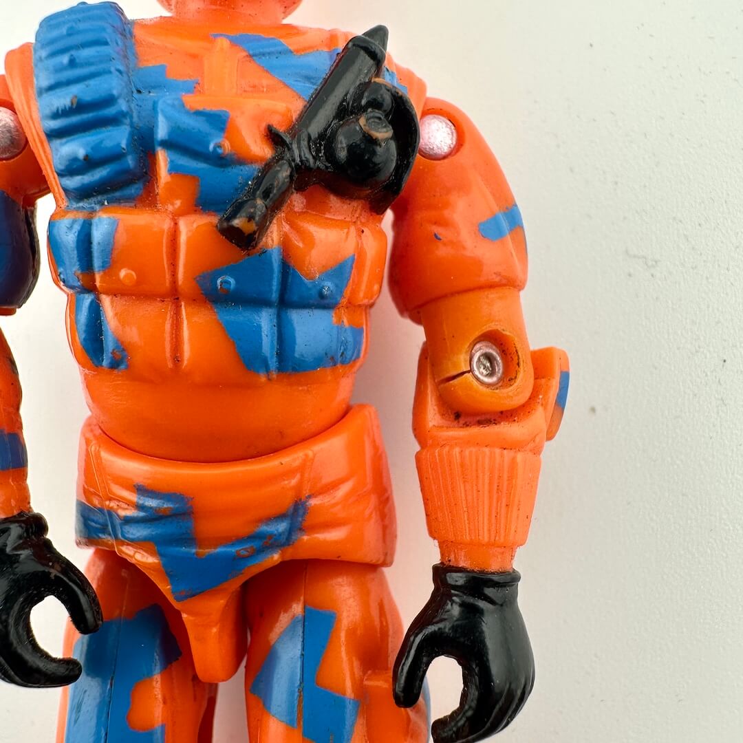 Close-up of an orange and blue action figure with black gloves on a light gray background