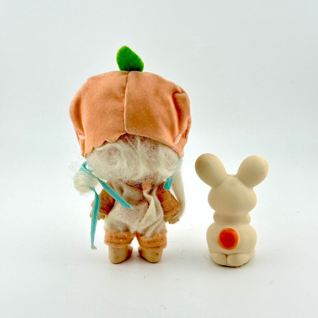 Toy baby doll with peach outfit and white bunny toy.
