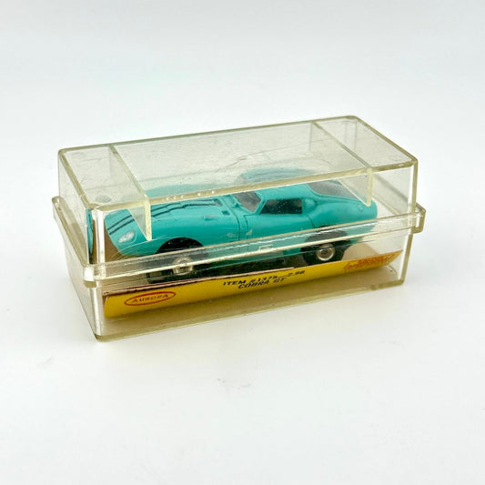 Turquoise model car in a clear display case on a white background