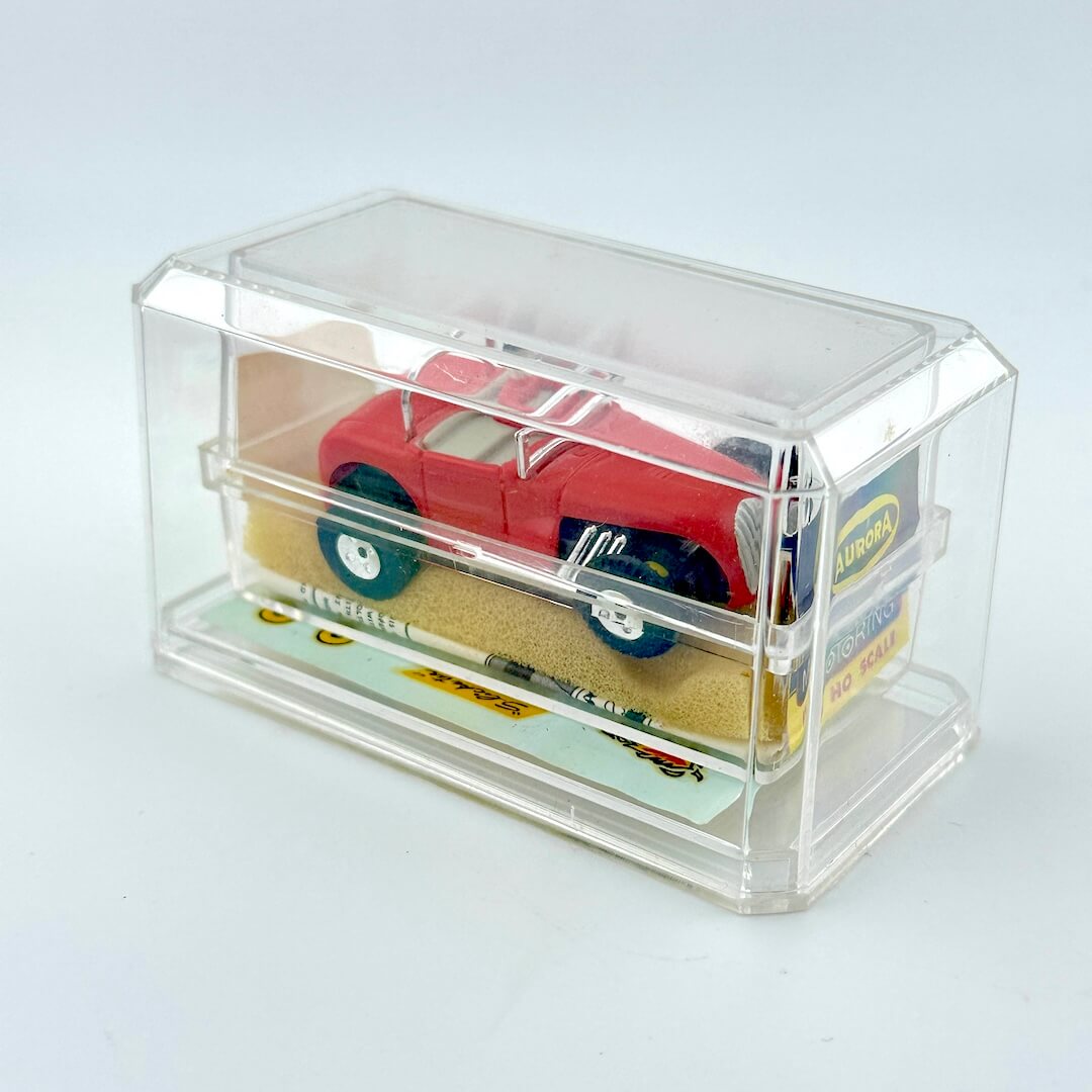 Red toy car in a clear display case on a light gray background