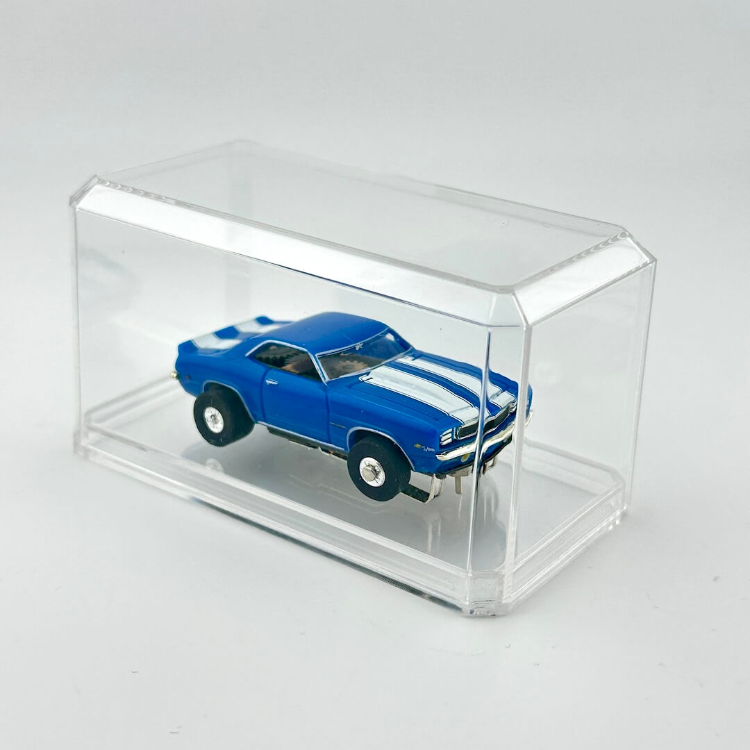 Blue model car with white stripes in a clear display case on a light gray background