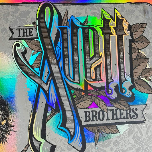 Close-up of "Avett Brothers" in stylized script on rainbow foil paper.