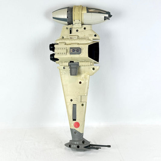 A vintage Star Wars toy spaceship, specifically a B-Wing fighter, in a light beige and gray color scheme.