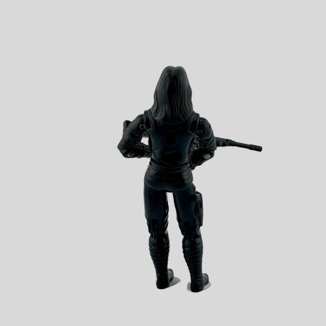 White woman with glasses dressed in all black with black rifle, red COBRA symbol on chest.