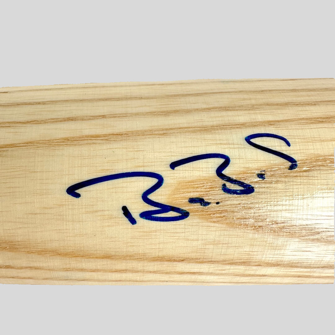 Signature in blue ink on a wooden bat.