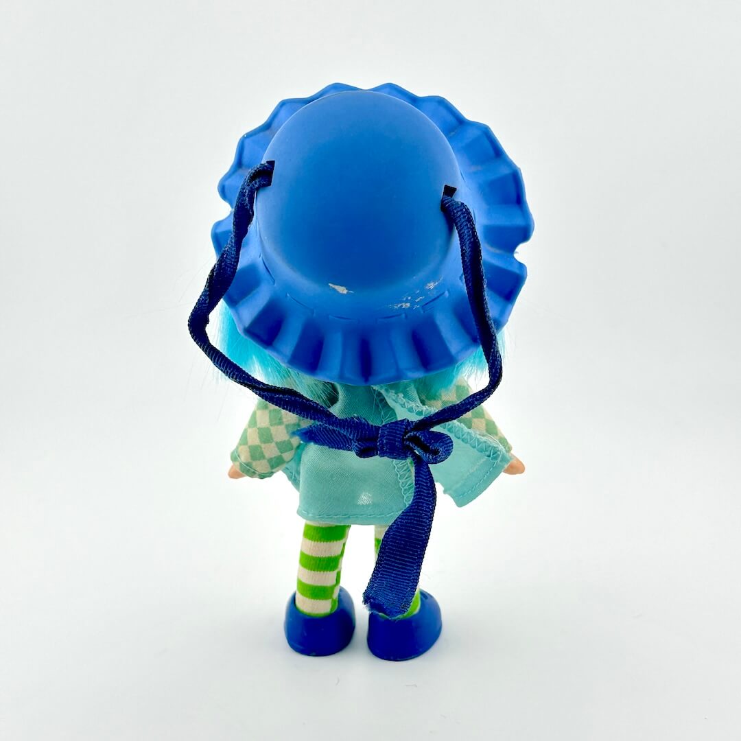 Small figurine with a blue hat and outfit on a white background