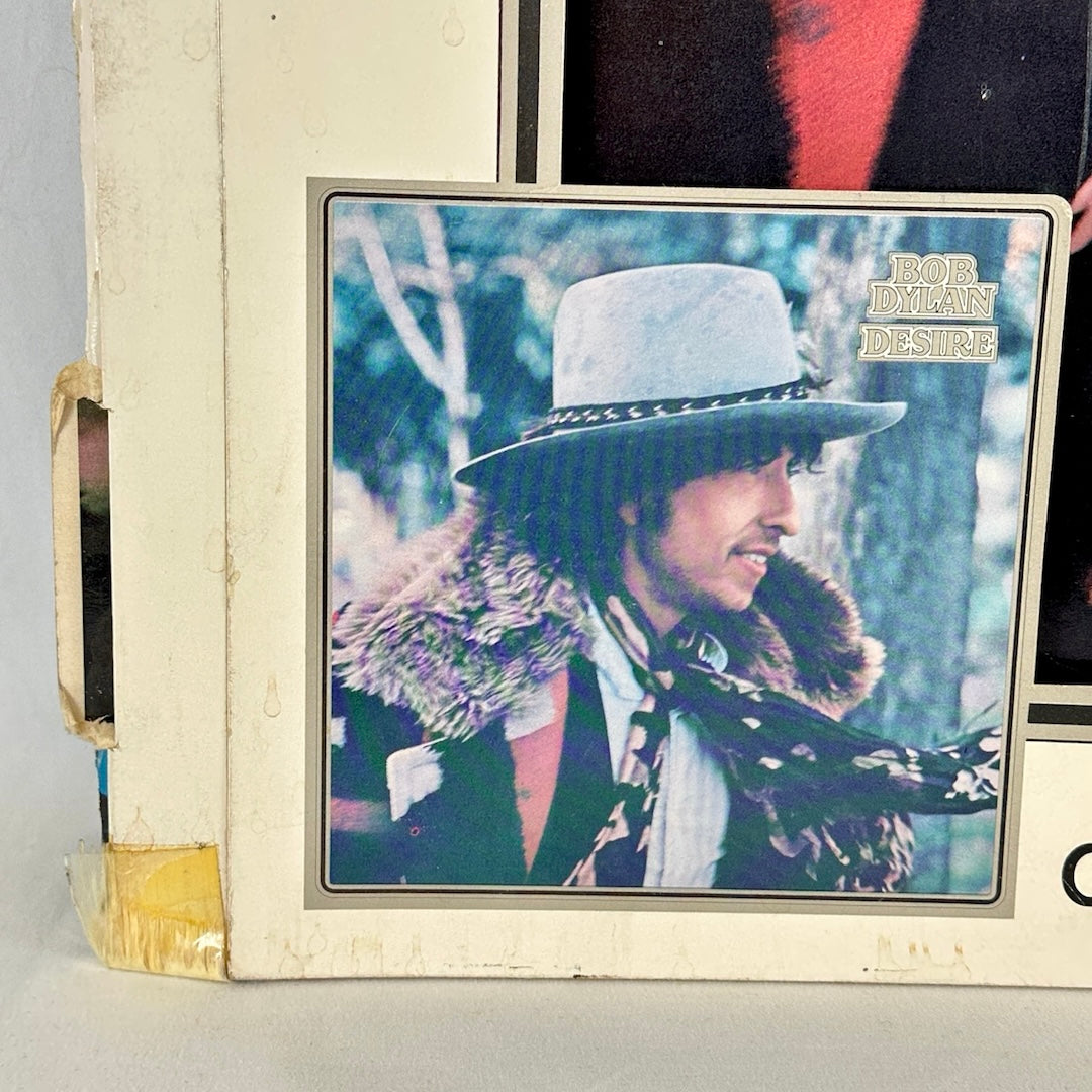 Bottom left corner of standee showing some tape at corner and some age/dirt indication.