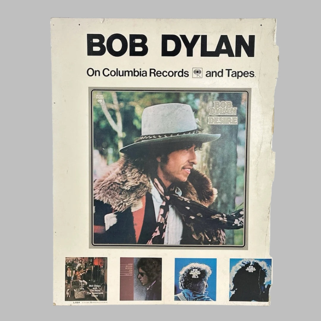 White rectangular sign with BOB DYLAN printed at top, color picture of Dylan in center, four album covers at bottom.