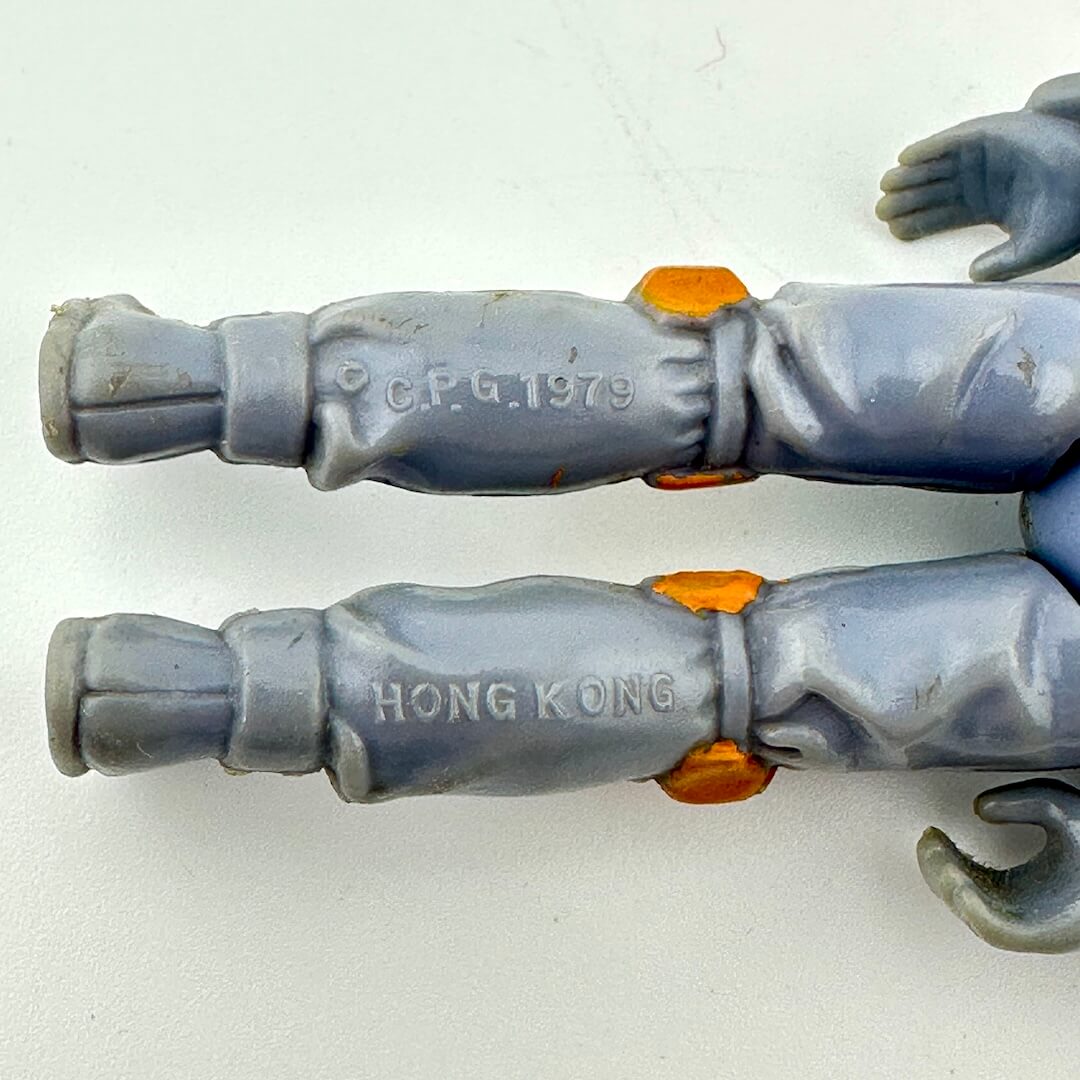 Close-up of a toy figure with 'C.F.G. 1979' and 'HONG KONG' text on gray arms.