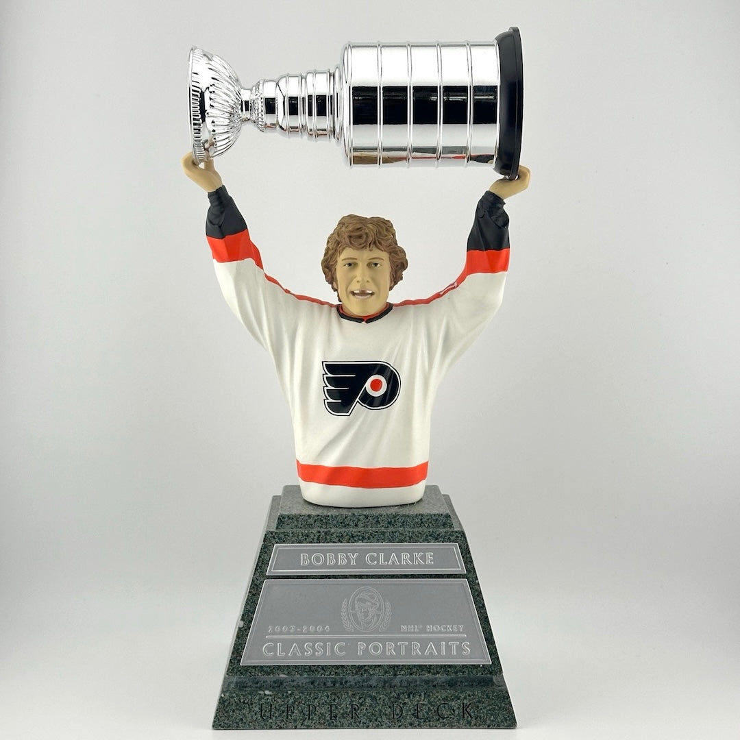 Faux marble pedestal with silver plaques, hockey player on top from stomach up, holding trophy above head.