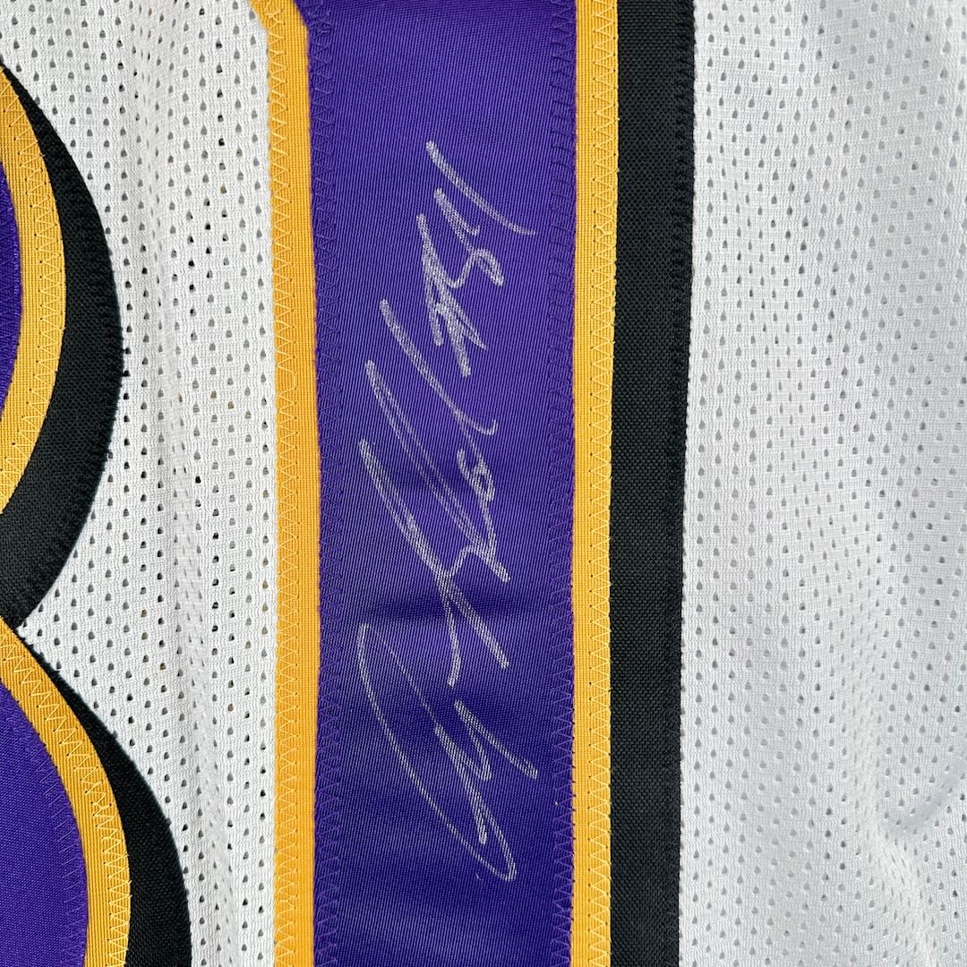 Close-up of a sports jersey with a signature on a purple stitched on number.