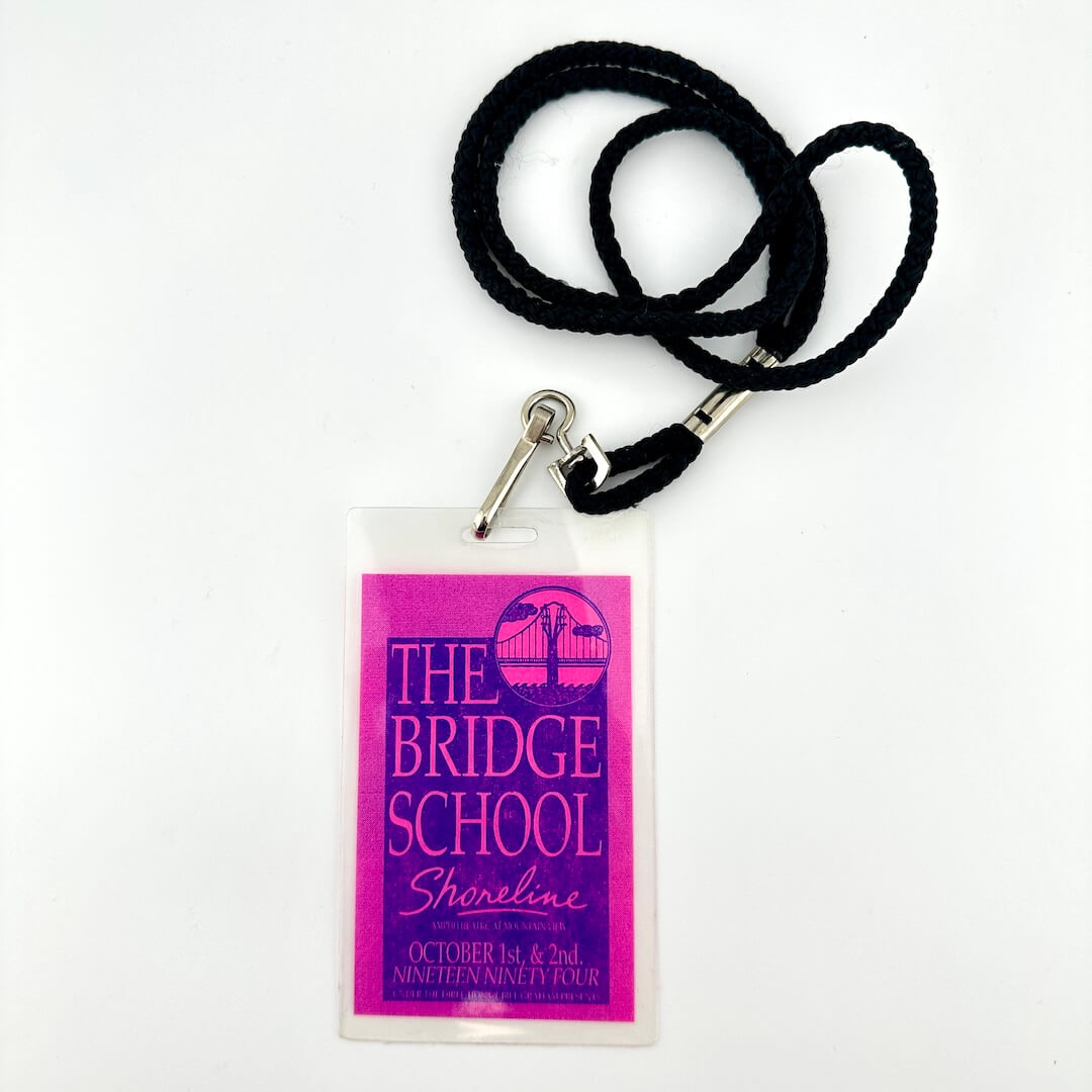 Lanyard with a pink and blue pass for 'The Bridge School' on a white background
