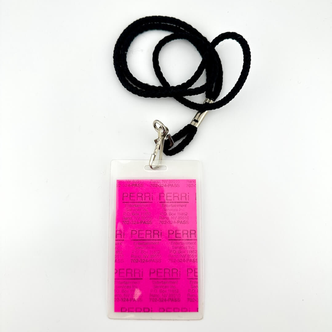 Lanyard with a pink and blue pass for 'The Bridge School' on a white background, backside view.
