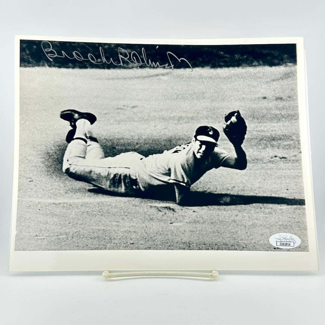 Black and white photo of a baseball player diving on a field with a signature above, displayed on a light gray background.
