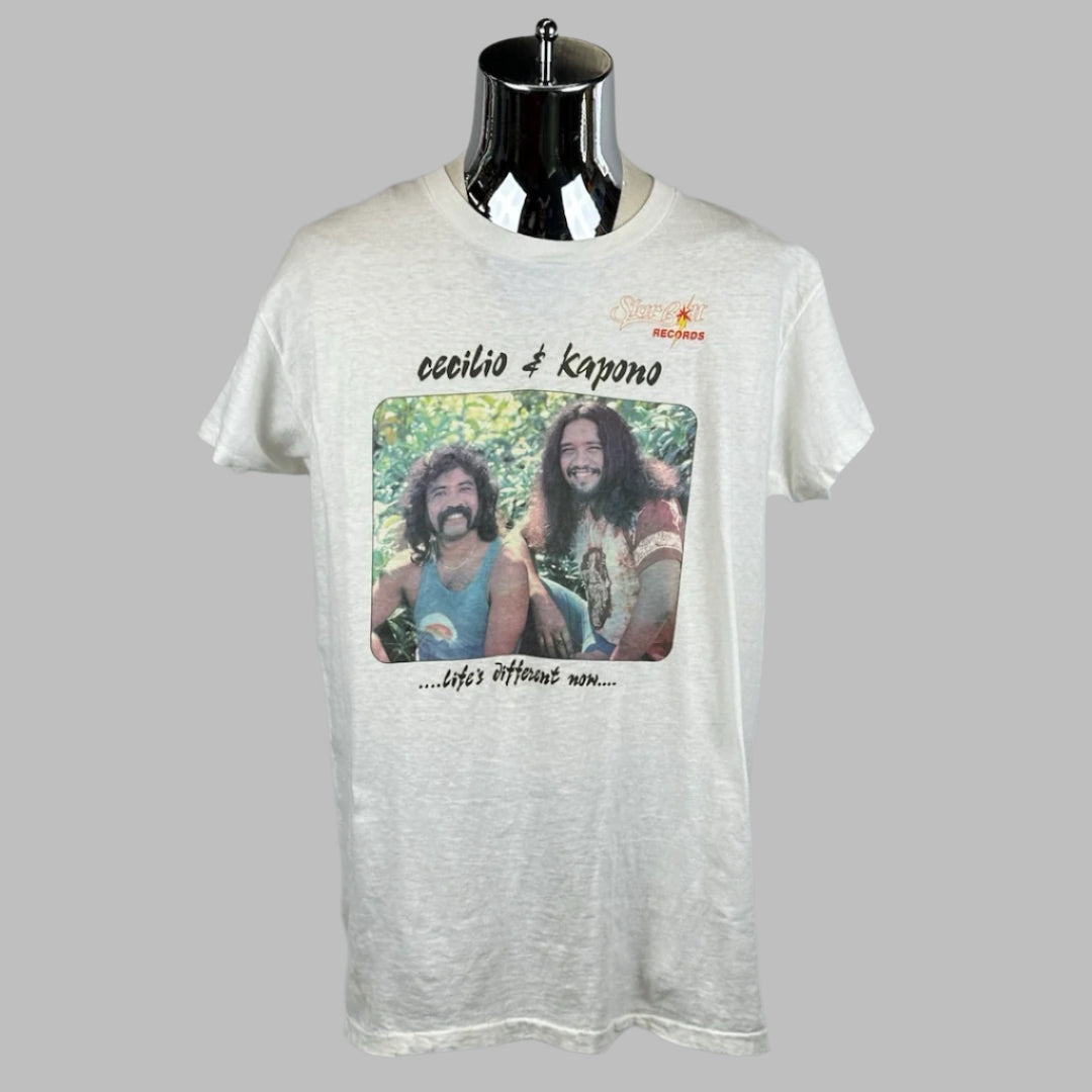 White short sleeve tee with photo of two men smiling with artist name above, motto below. Record label logo on right breast.