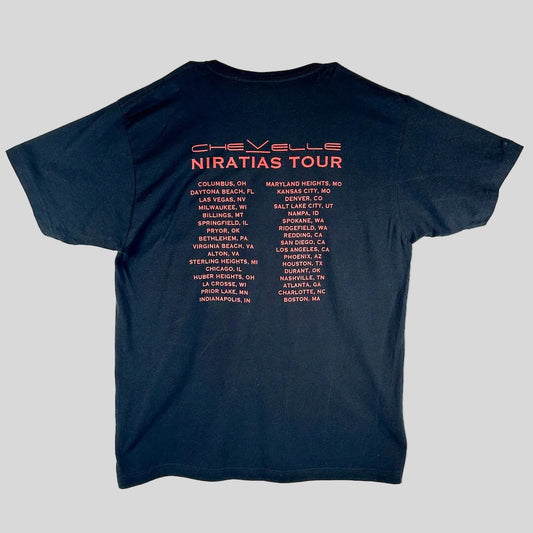 A black short-sleeve t-shirt, showing the back side printed with the words 'Chevelle Niratias Tour' in red and a list of tour cities.