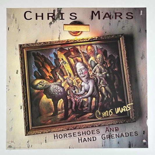 Square poster with gold framed art hanging crooked under small gold light. Cover painting: Horseshoes by Mars. Signed in gold