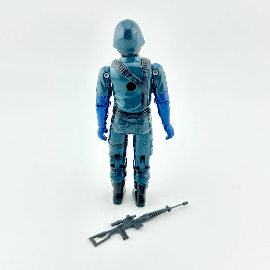Action figure in blue outfit with gun accessory against white background.