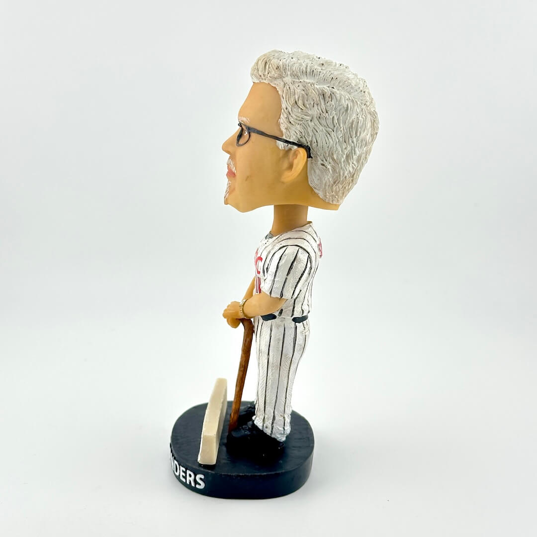 Bobblehead figure of a person with gray hair, glasses, and a striped suit holding a cane on a white background.