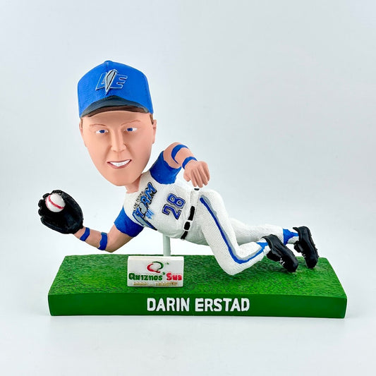 Bobblehead figure of a baseball player in a blue and white uniform on a green base with a white background