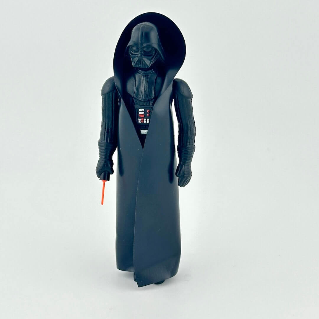 Toy figure of a character in dark costume with a red light saber on a white background