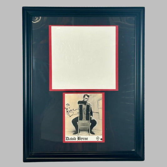 Black frame with black matting. Red matting outlining white embossed promo poster square above signed picture.