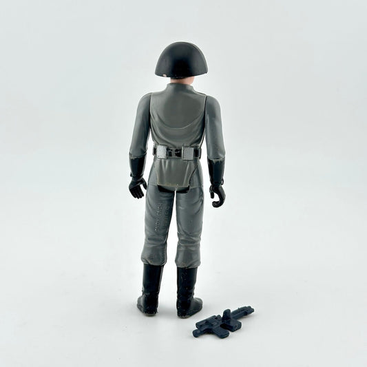 Back of action figure in gray military uniform with black helmet and weapon on white background.