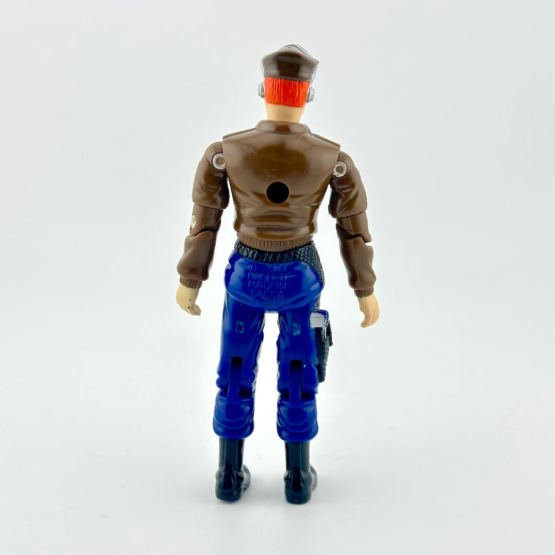 GI Joe action figure in blue pants, brown jacket, with aeronautical hat, photographed on white background.
