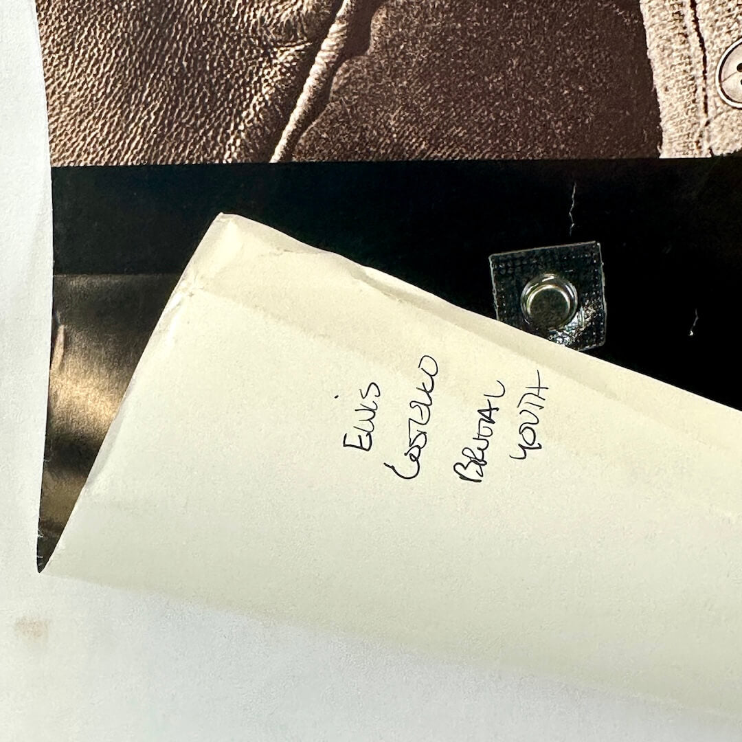 Bottom left corner curled up to show pen note on reverse side.