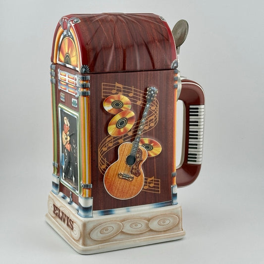 Jukebox shaped stein with guitars in relief on sides, full color Elvis on front, keyboard on handle. Pewter thumb lever.