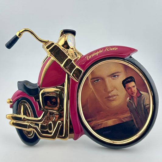 Motorcycle shaped ceramic plate with Elvis portrait in front wheel of him in the sunset above dressed in grey in foreground.
