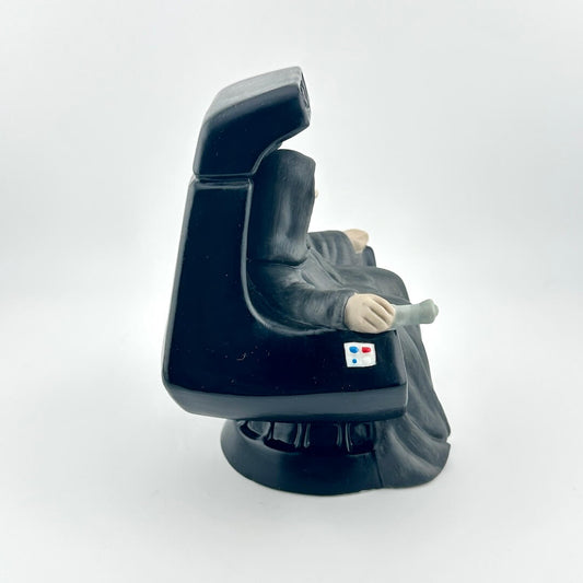 Ceramic figurine of the Star Wars Emperor in throne against white background.