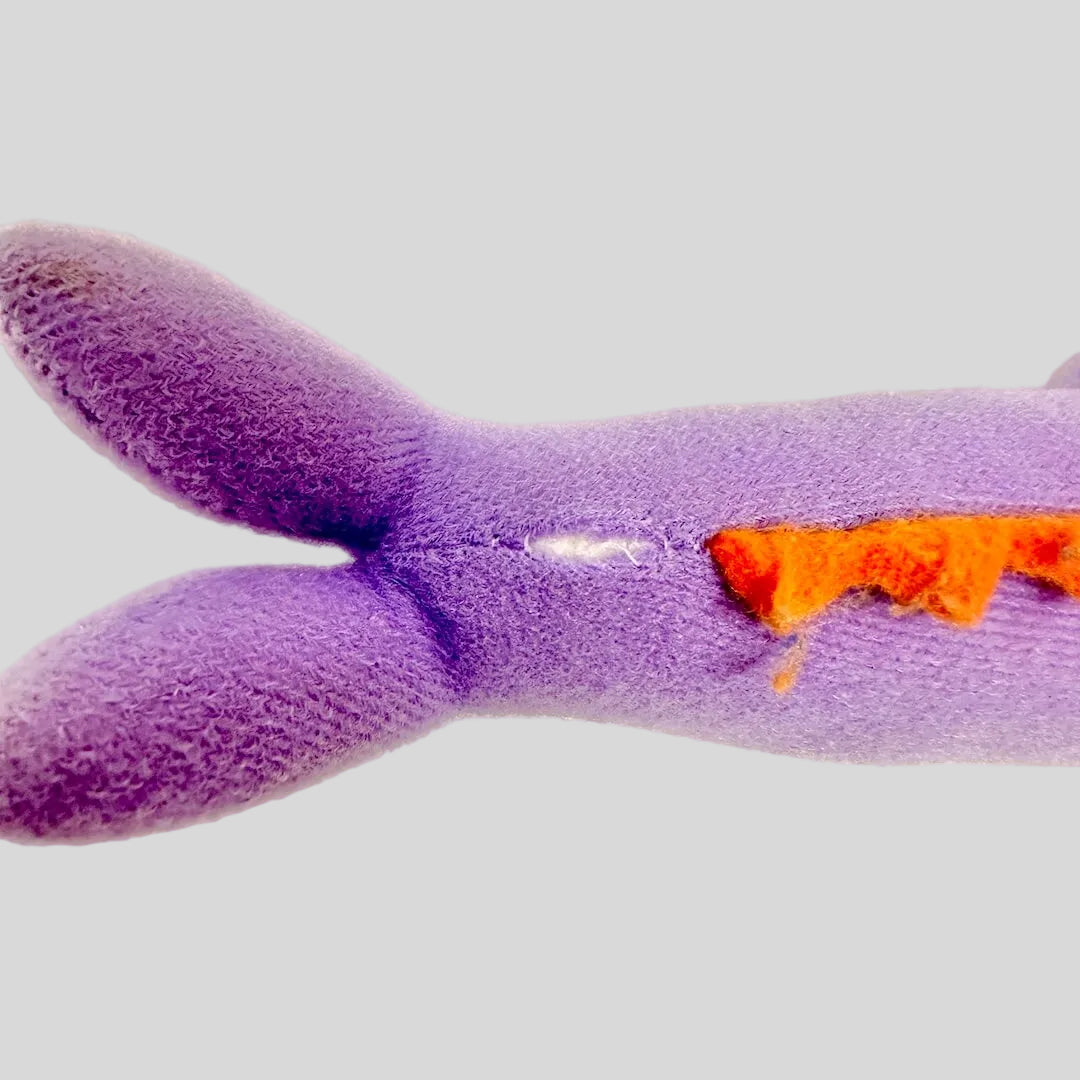 Purple plush toy with orange spine on a white background
