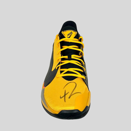 Yellow and black sneaker with a signature on a white background