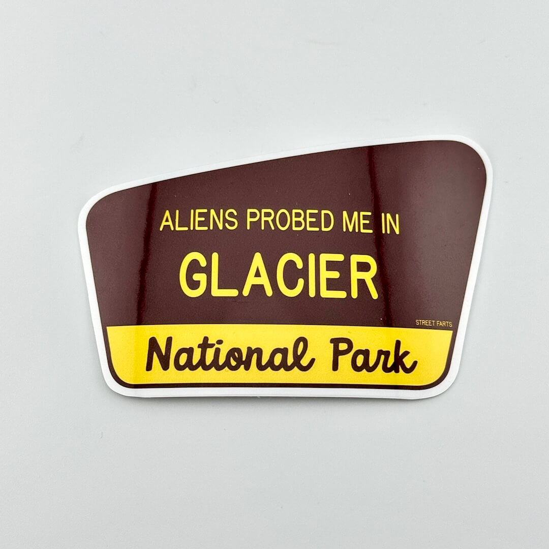 Sticker with text 'ALIENS PROBED ME IN GLACIER National Park' on a brown and yellow background