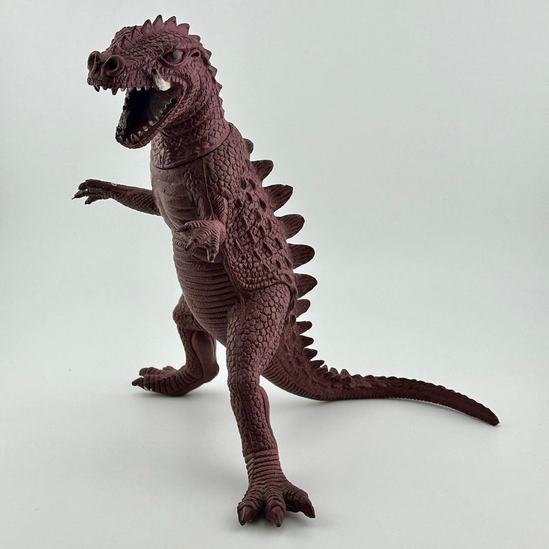 Front-side view of purple dinosaur type animal with white tusks & teeth, black eyes, long tail.