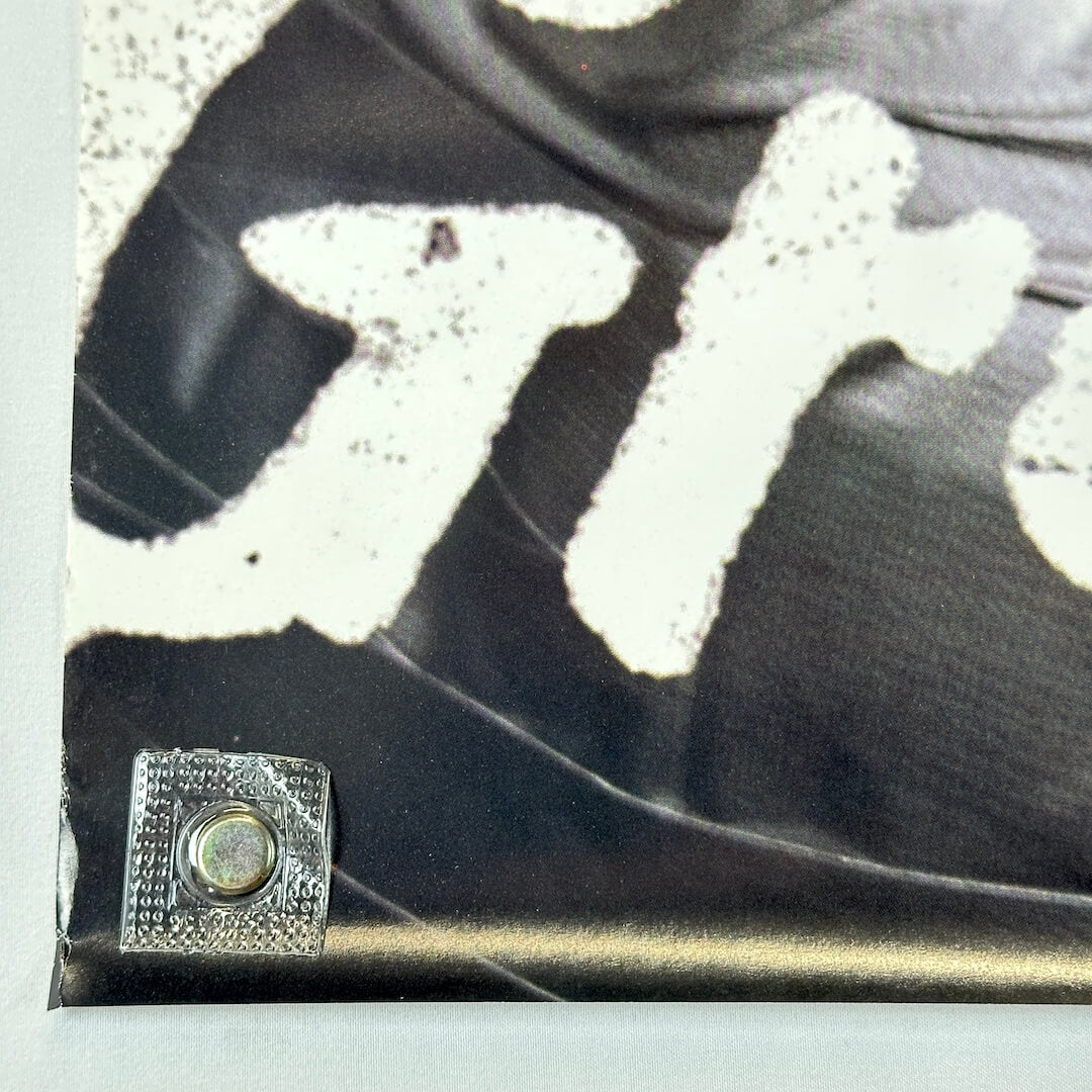 Bottom left corner of poster with slight bump to edge.