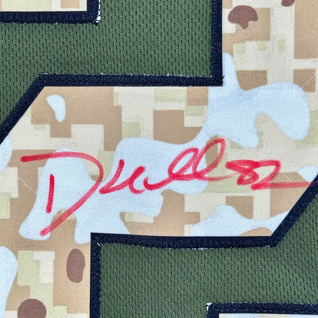 Camouflage sewn on number with red marker signature on a green jersey background.