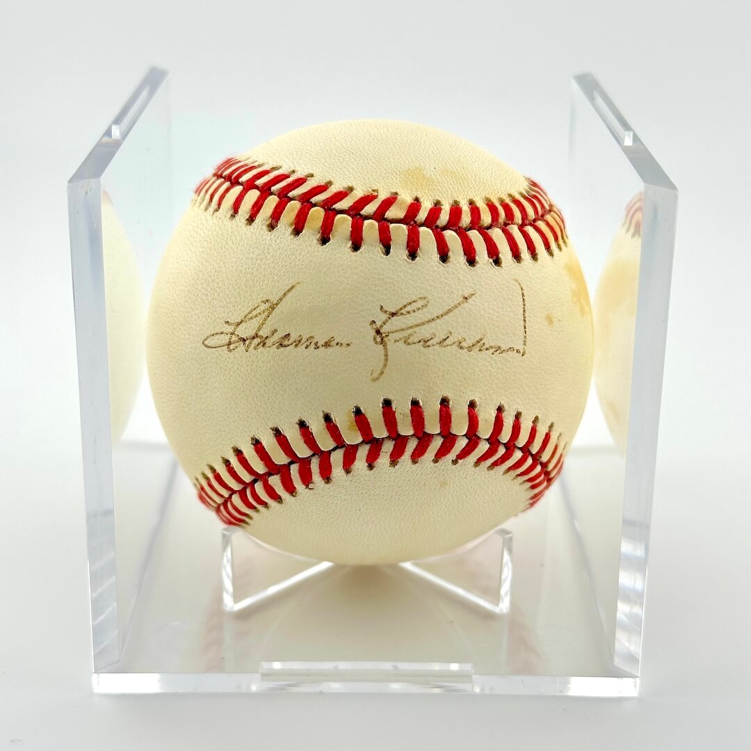 Signed baseball in clear display against white background.