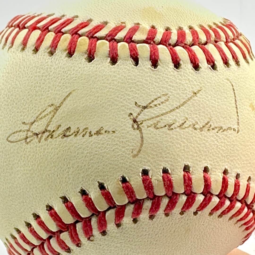 Close up of signed baseball in clear display against white background.