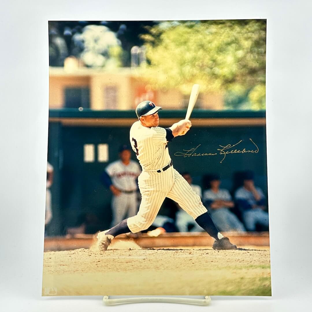 Baseball player in vintage uniform swinging a bat on a field with blurred background