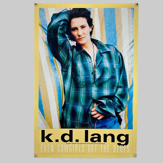 K.D. Lang in plaid shirt standing in front of striped background with yellow border. Album info along bottom.