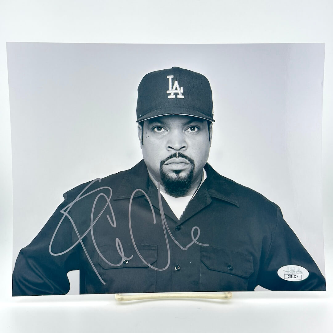Black and white photo of Ice Cube wearing a cap with a logo, signed on a white background