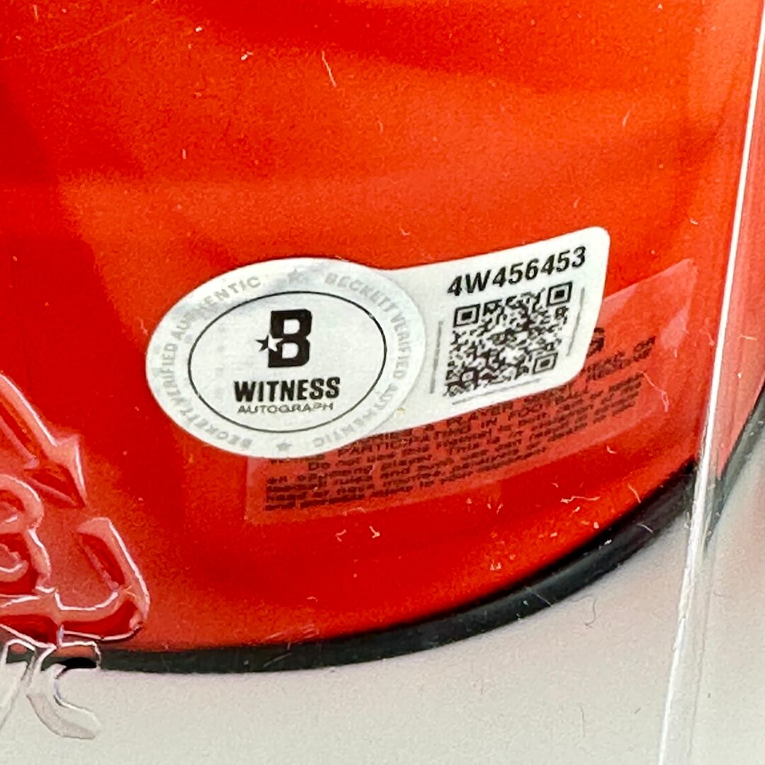 Close-up of a orange surface with a 'Witness Autograph' label and QR code.