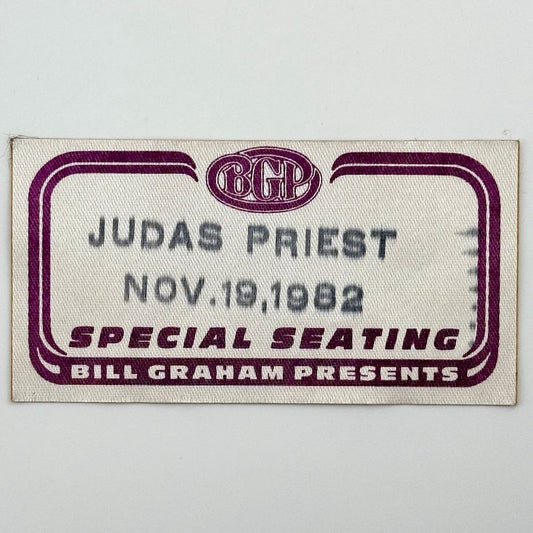 White rectangular fabric backstage pass with maroon line border, and black stamp with artist  event date.